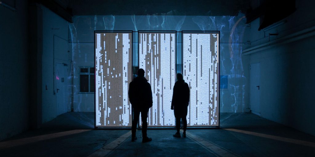 two people infront of an illuminated wall